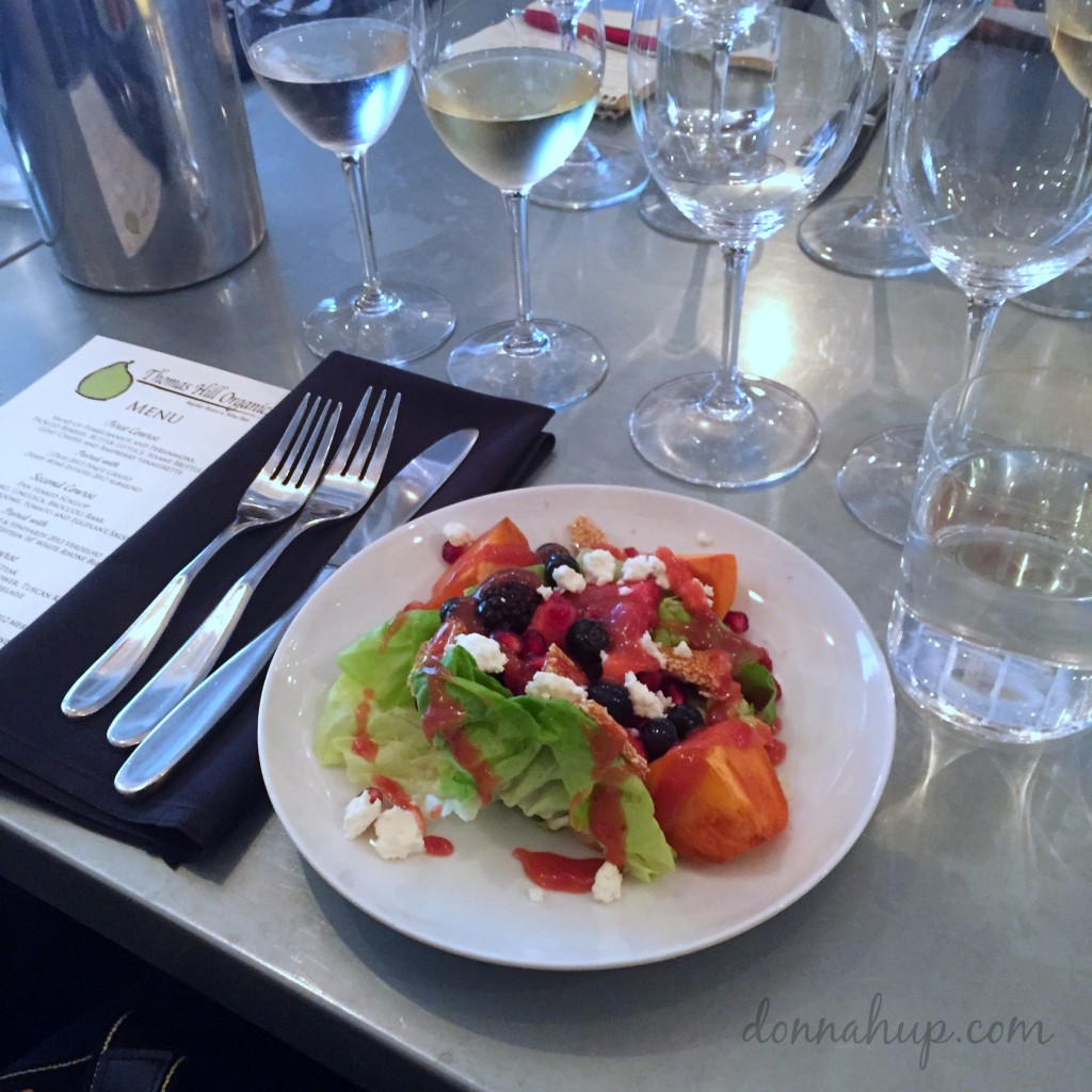 Colorful salad with numerous wine glasses at the table.